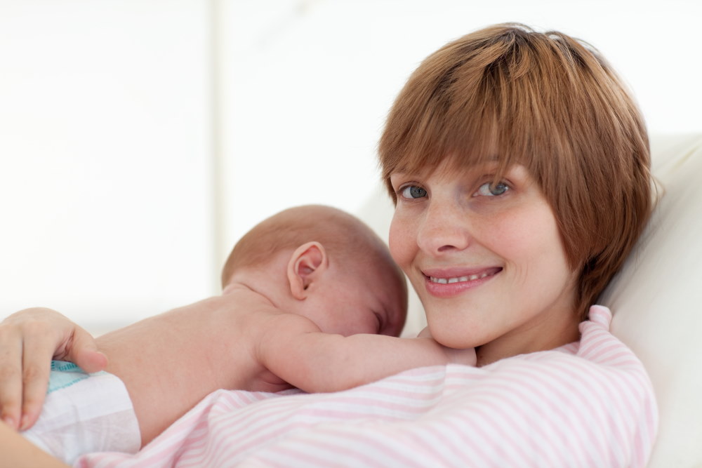 Ευτυχισμένη μητέρα με το νεογέννητο στην αγκαλιά της